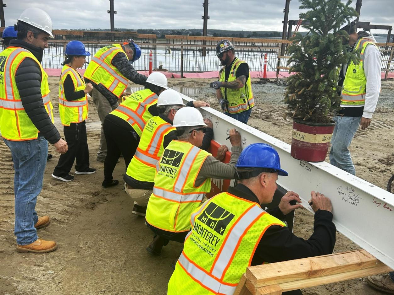 MRY staff, board members, and project stakeholders take turns to sign the final beam.