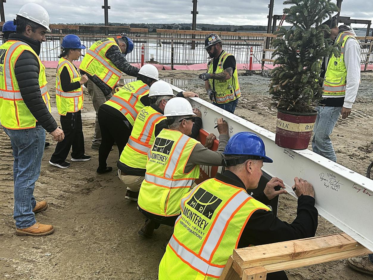 MRY staff, board members, and project stakeholders take turns to sign the final beam.