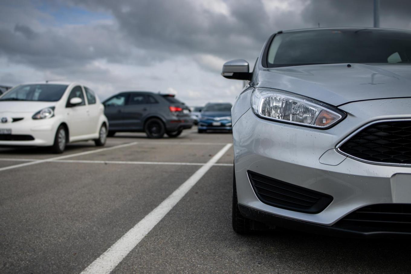 A white car and a silver car in a parking lot.