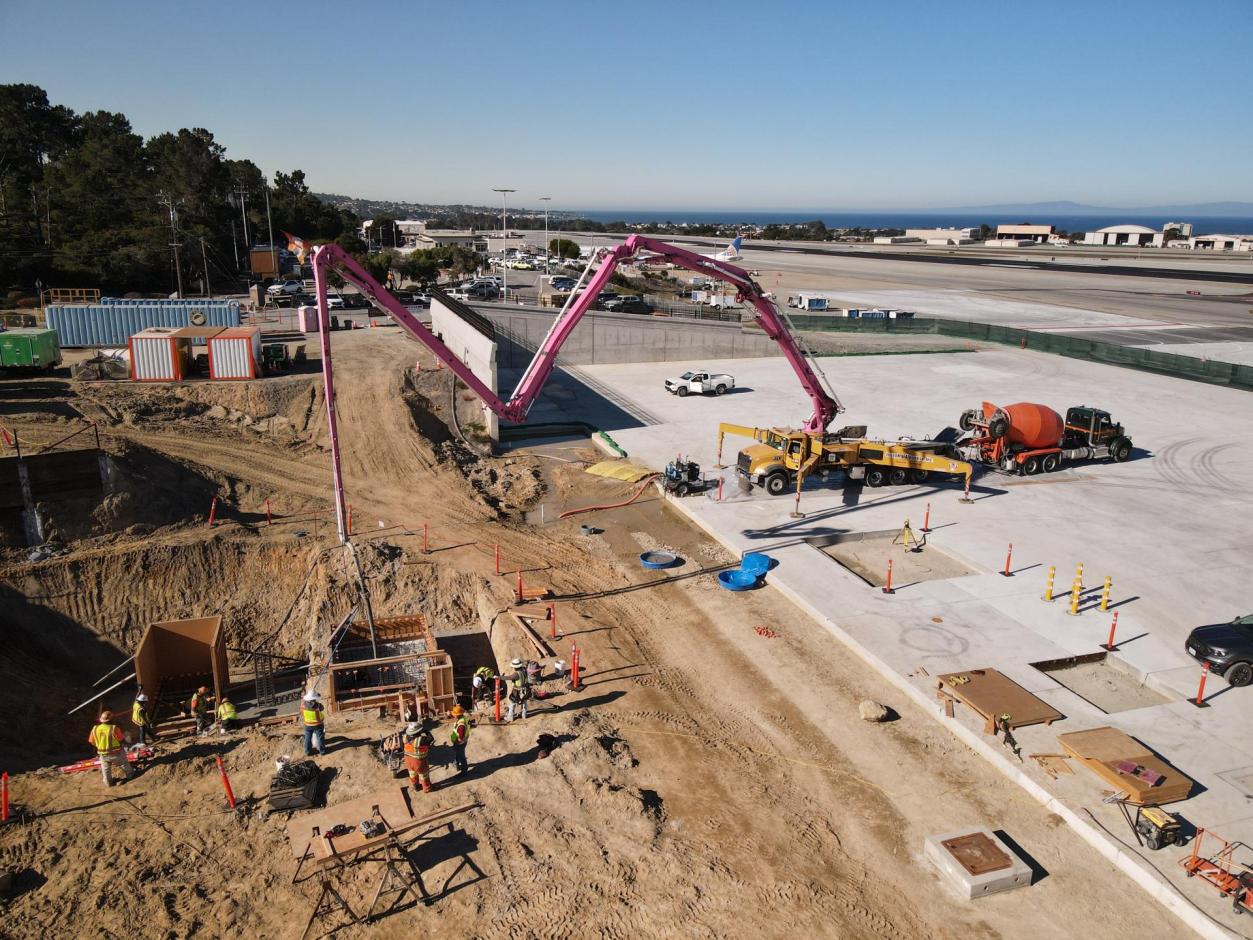 Westward view of workers laying concrete for the service elevator pit.