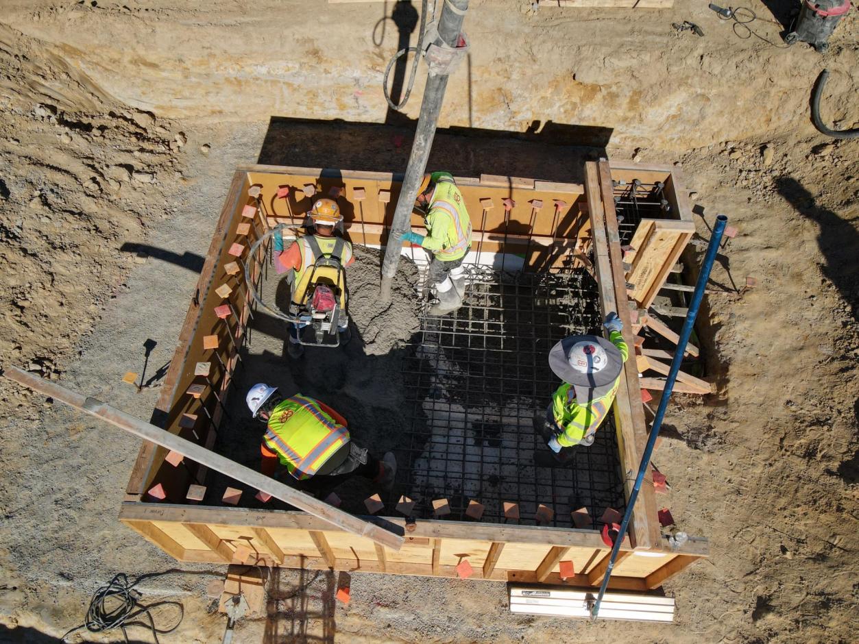 Workers laying concrete to form the pit of the terminal's service elevator.