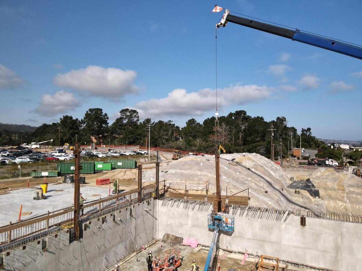 Ironworkers help the crane operator guide the steel columns into place.