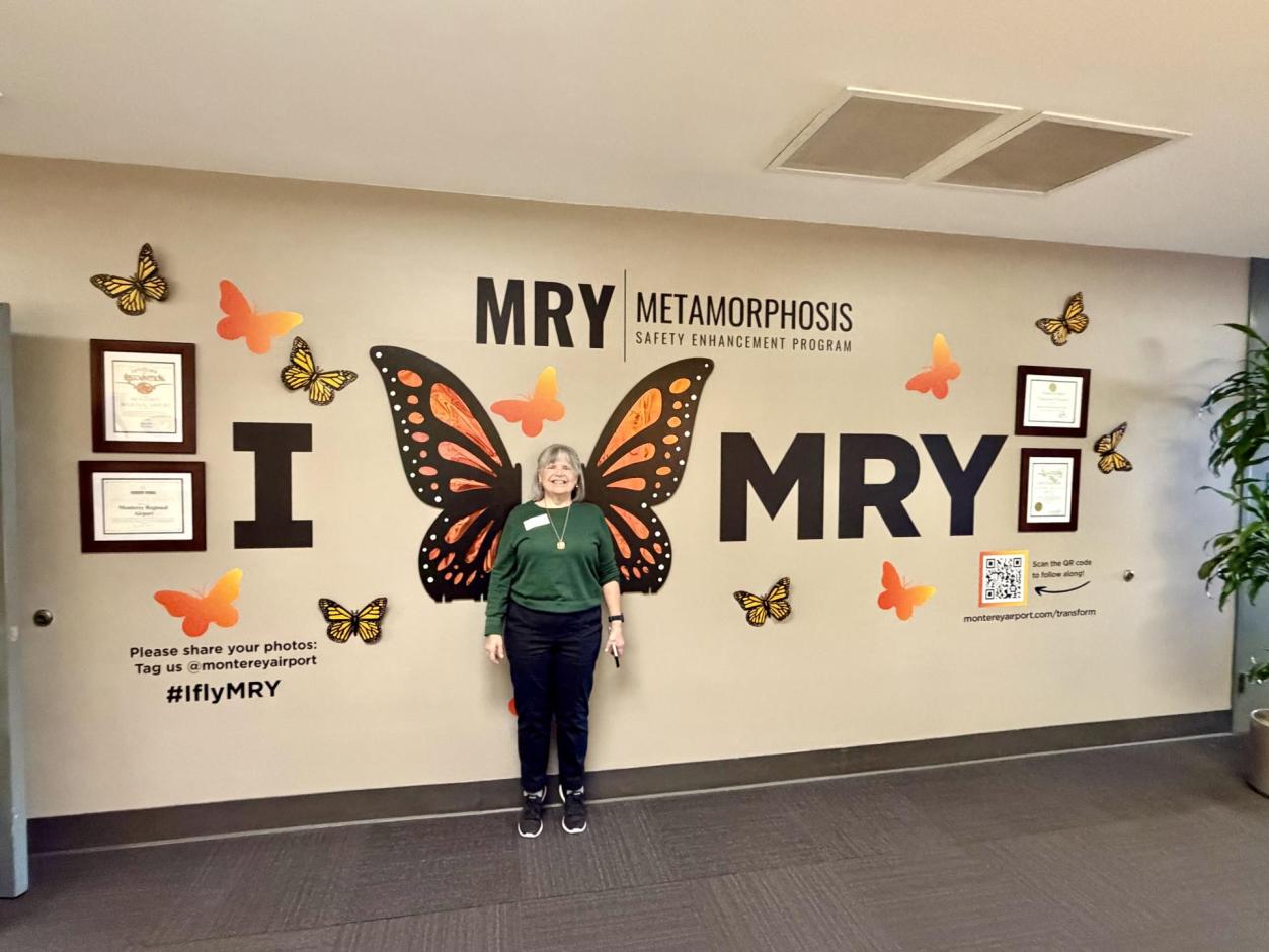 Lady standing under the MRY Metamorphosis display in the terminal.