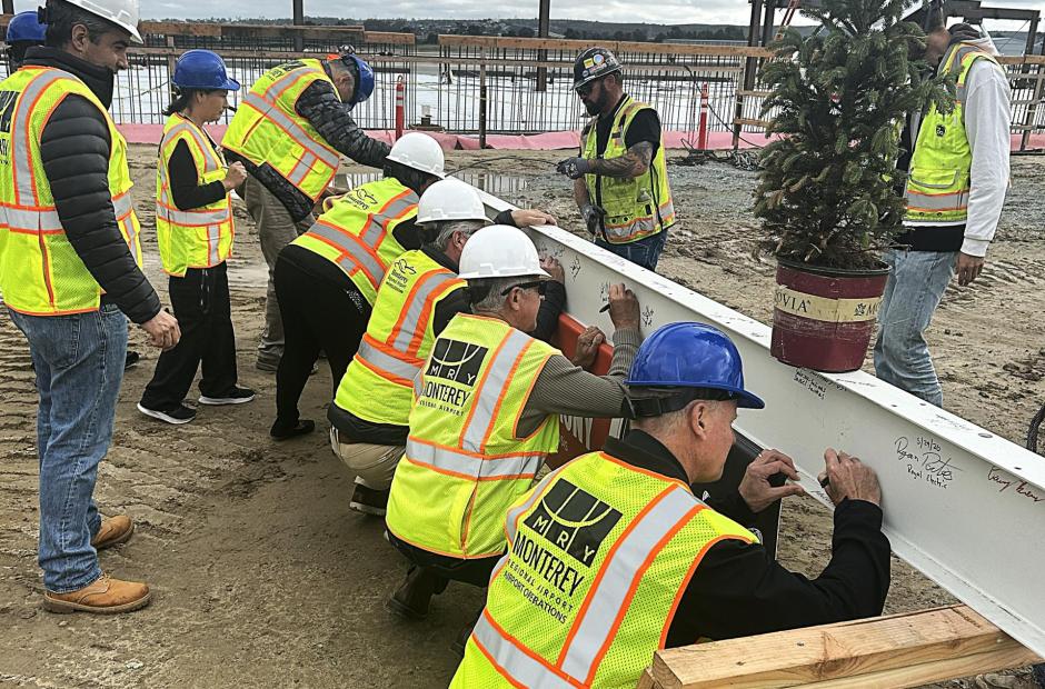 MRY staff, board members, and project stakeholders take turns to sign the final beam.
