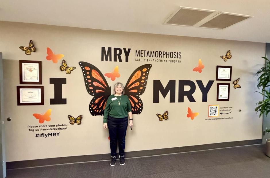 Lady standing under the MRY Metamorphosis display in the terminal.