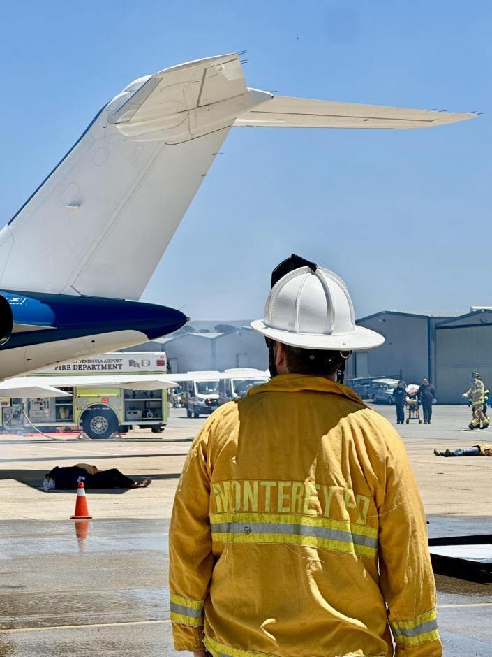Firefighter looking at plane with a fire truck in the background.