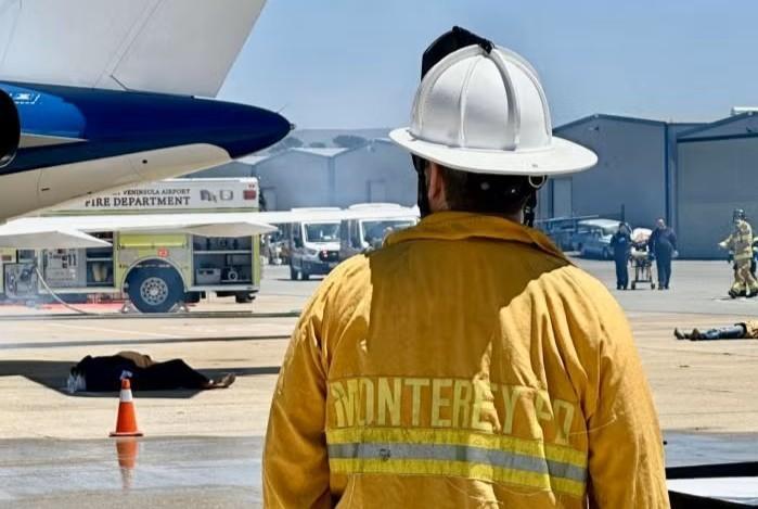 Firefighter looking at plane with a fire truck in the background.
